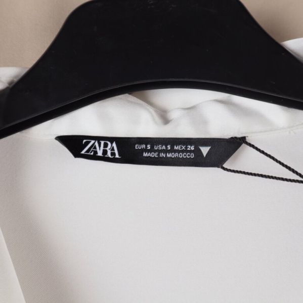 Närbild på Zara etiketten på vit klänning
