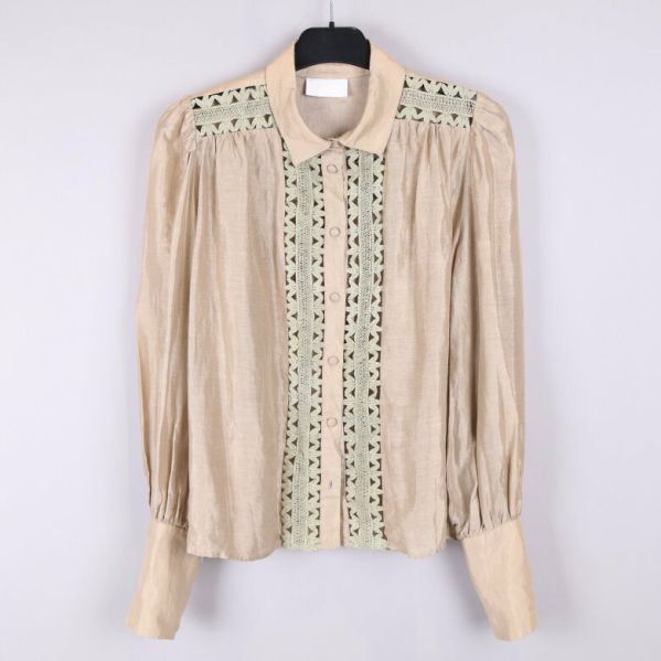 Framsidan av beige blus med spetsdetaljer