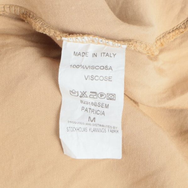 Materialetikett på beige klänning visar 100% viskos