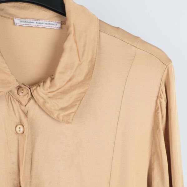 Detaljbild på krage och knappar på beige klänning