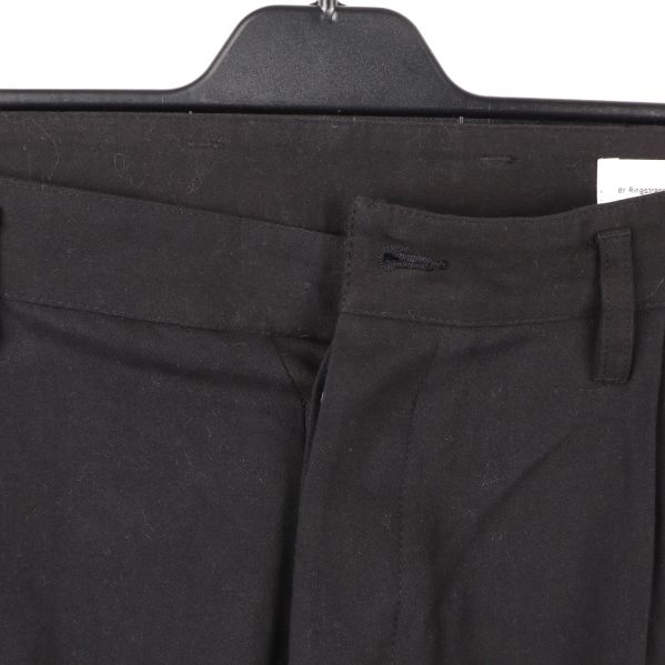 Närbild av midjan på svarta cargobyxor, knapp saknas