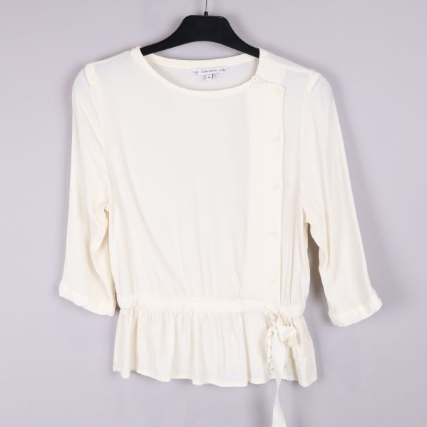 Vit blus framifrån med knappar och knytband