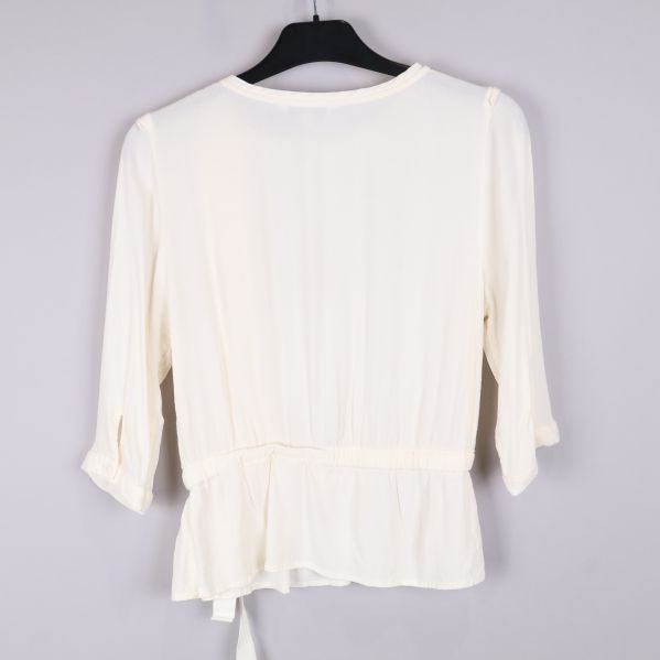 Vit blus bakifrån med plisserad detalj