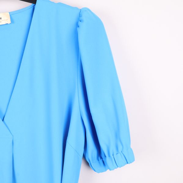 Närbild av klännings ärm i blått tyg