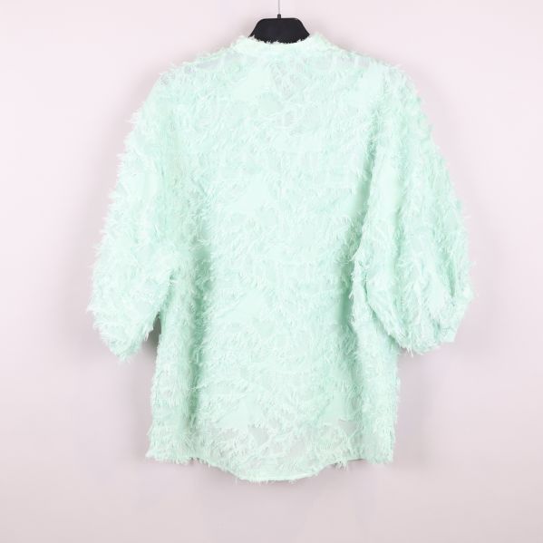 Baksidan av mintgrön blus med fransar