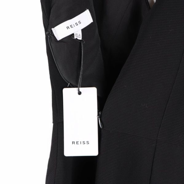 Vit etikett med Reiss-logotyp hängande från klänningen