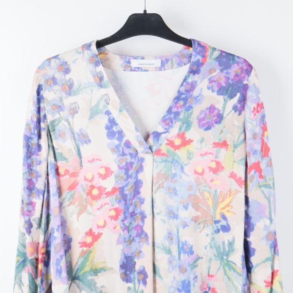 Närbild på blusens blommönster och v-ringning