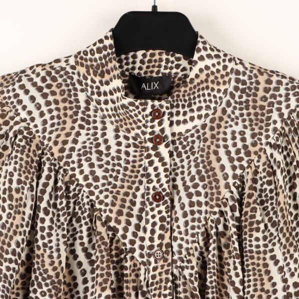 Närbild på blusens djurmönster och knappar