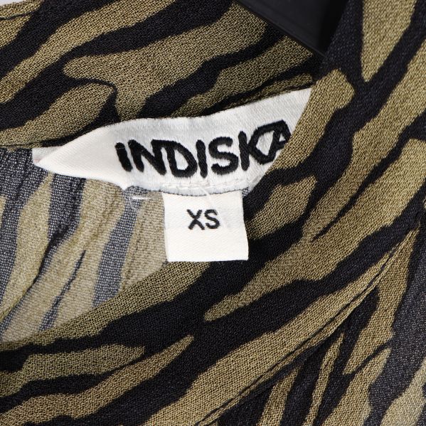 Närbild på etikett med varumärket: Indiska, och storlek: XS