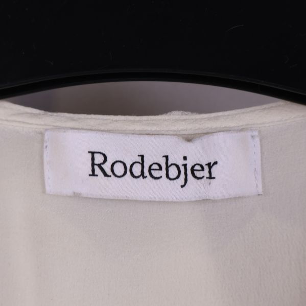 Närbild på Rodebjer logotyp på blusen
