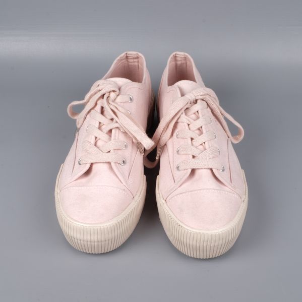 Sidan av ljusrosa sneakers med detaljsöm och platåsula