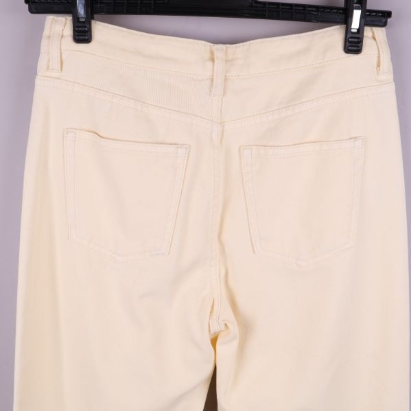 Närbild på bakfickor av krämfärgade jeans