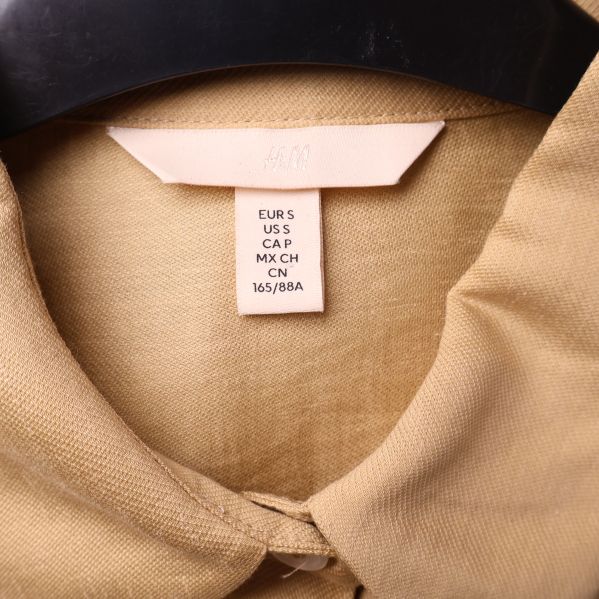 Storlekstag på beige skjortklänning, visar EUR S