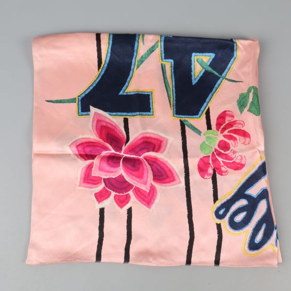 Närbild på scarfens blommönster med text