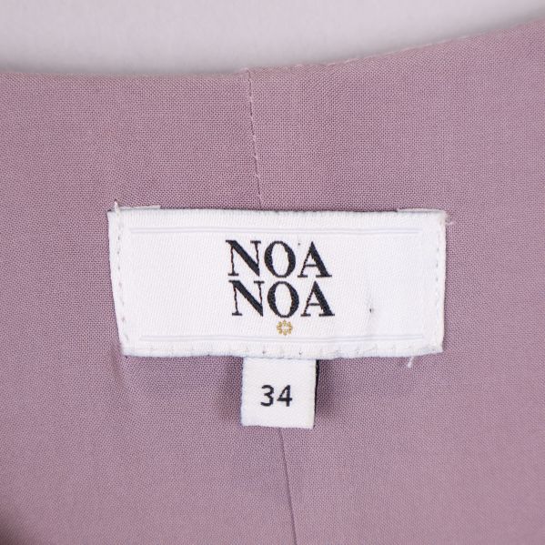 Vit etikett med Noa Noa logotyp