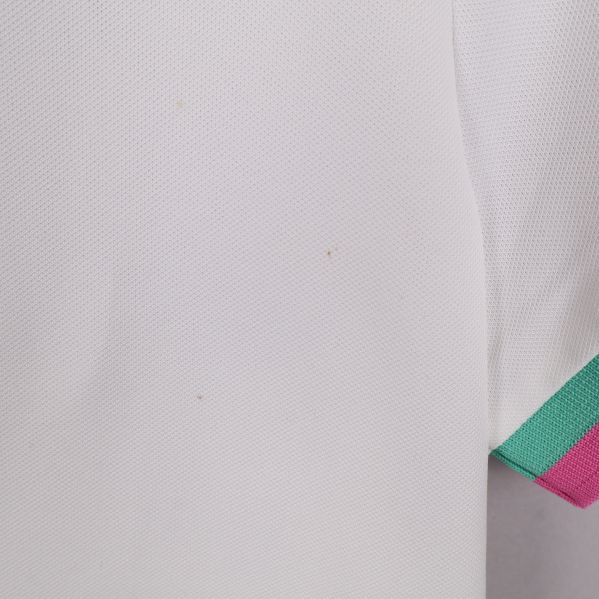 Närbild på vit pikétröja med färgade detaljer