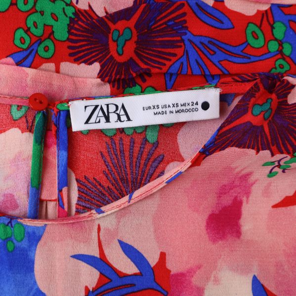 Närbild på ZARA etikett på blommig blus