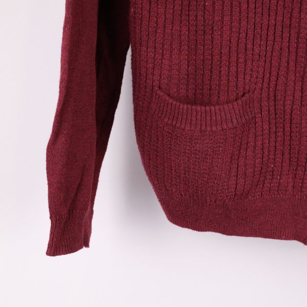 Närbild på ärmslut och fickan av vinröd cardigan