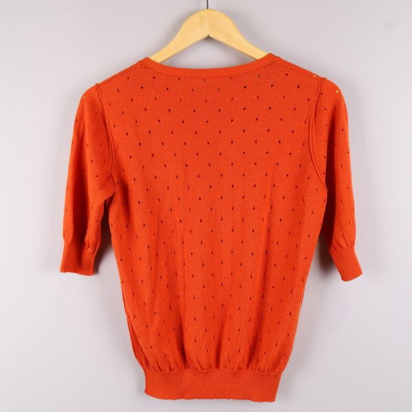 Baksidan av orange tröja med perforerat mönster