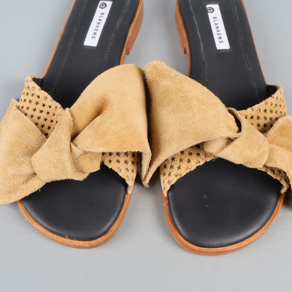 Närbild av sandaler med perforering och rosetter