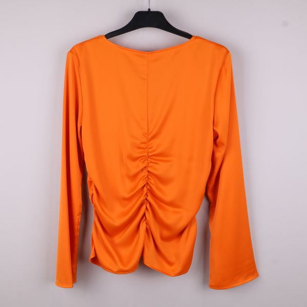 Baksidan av orange blus med rynkor