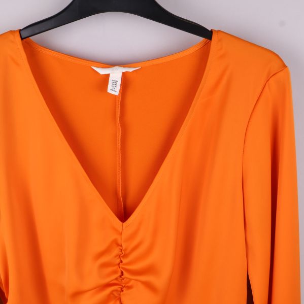 Närbild av etikett på orange blus