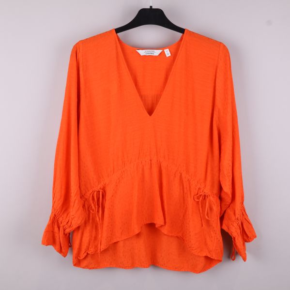 Orange blus med volanger framtill 