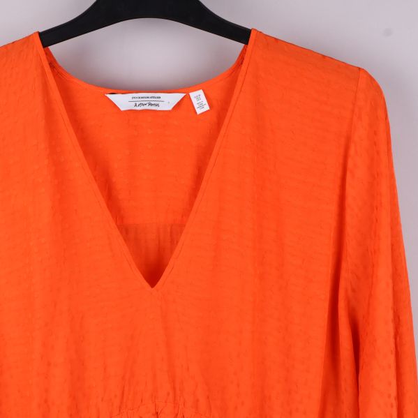 Närbild på framdelen av orange blus