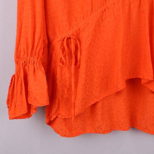 Ärmdetaljer med knytband på orange blus