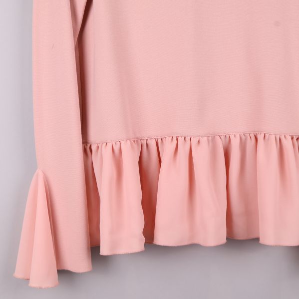 Närbild av rosa blusärmar med volang