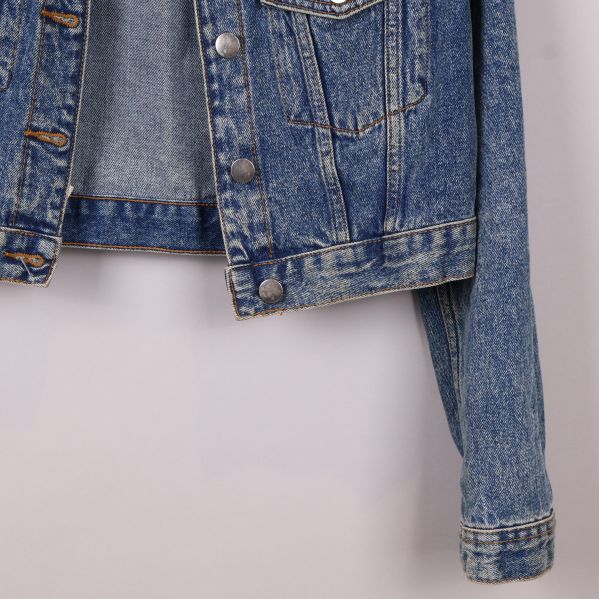 Ärmdetalj på blå jeansjacka med knapp
