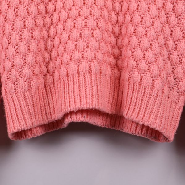 Närbild av nederdelen på rosa stickad tröja