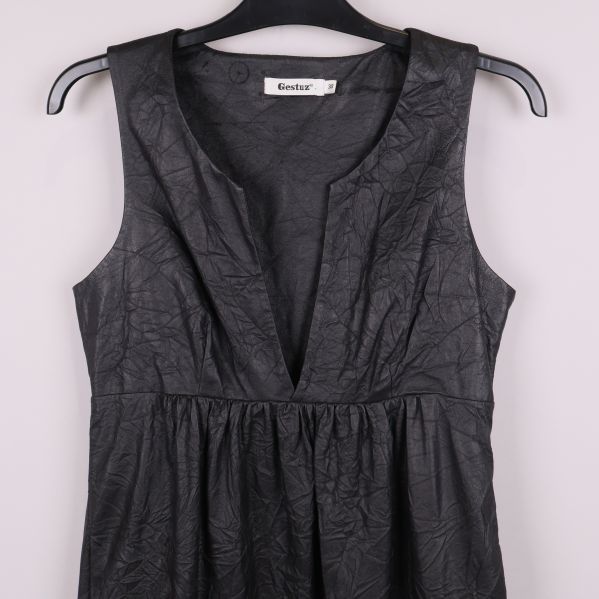 Närbild på överdelen av svart klänning med v-ringning