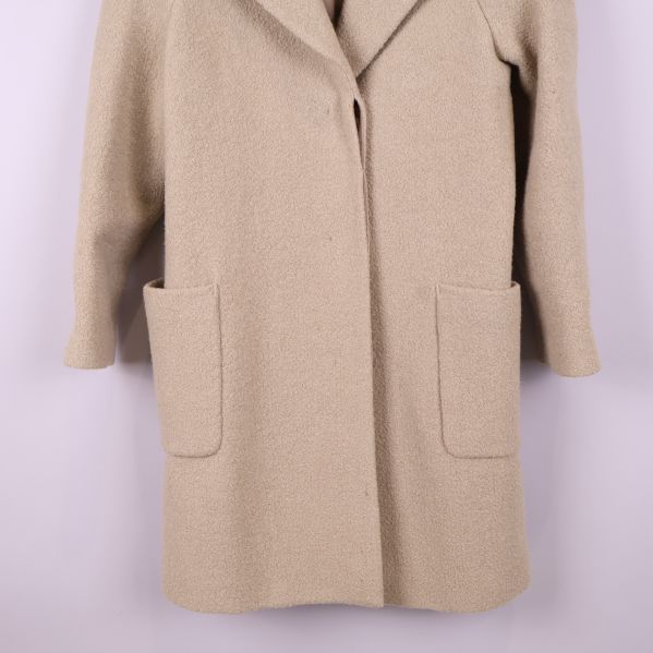 Närbild av stora patchfickor på beige kappa