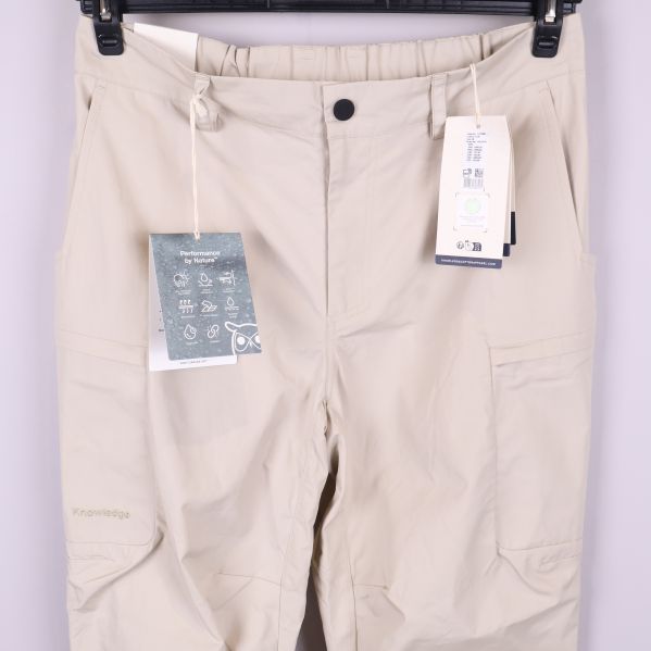 Närbild på framsida med fickor och etiketter på beige byxa