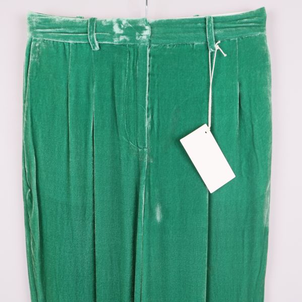 Närbild på midjedetaljer samt hällor och etikett på gröna sammetsbyxor