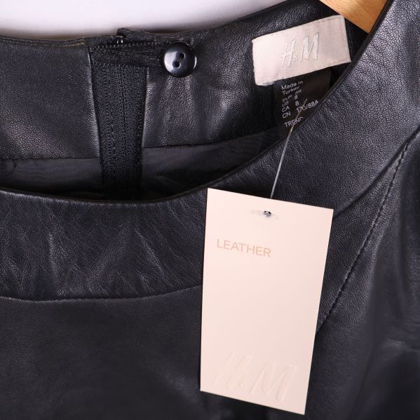 Närbild på krage med H&M-lapp och märkning LEATHER