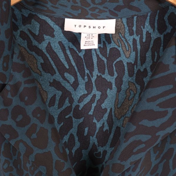 Närbild på krage och etikett med TOPSHOP-logga i klänningen
