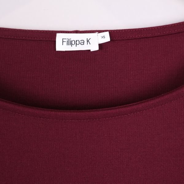 Närbild på halsringning och varumärkestagg Filippa K