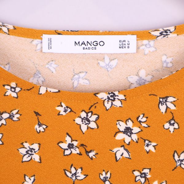 Närbild av etikett med Mango-logo i halsen