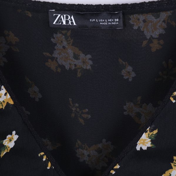 Närbild på ZARA-etikett i blommig svart blus