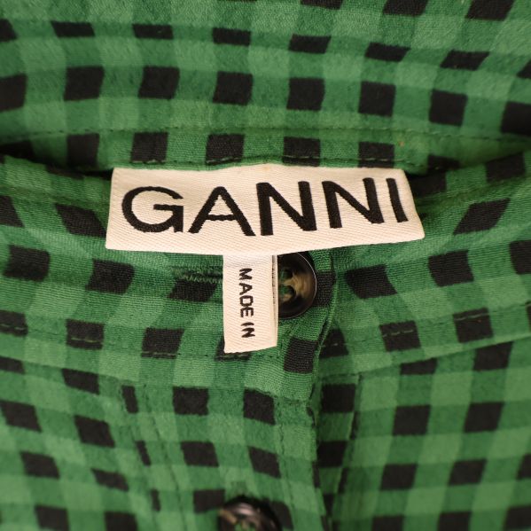 Närbild på GANNI-märke på grön rutmönstrad kjol
