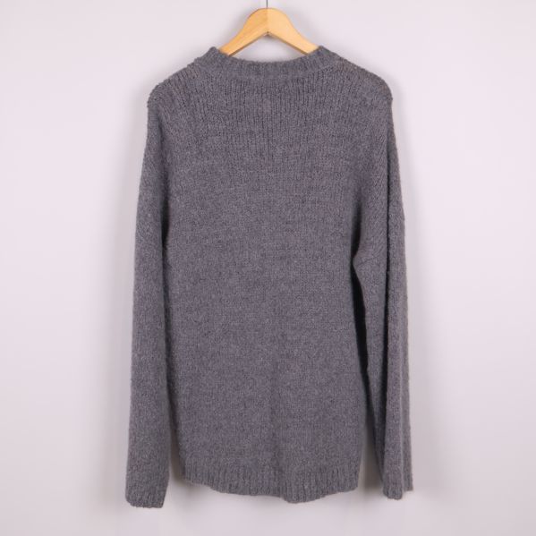 Grå stickad tröja bakifrån på galge