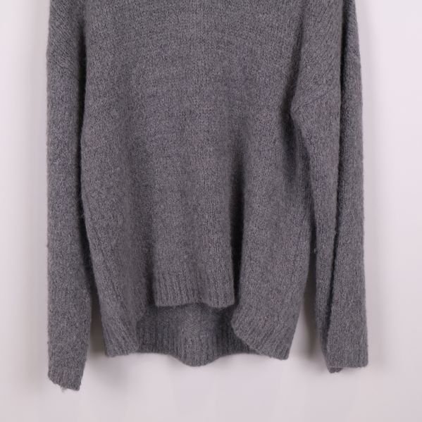 Närbild på nederdel och ärm av grå stickad tröja