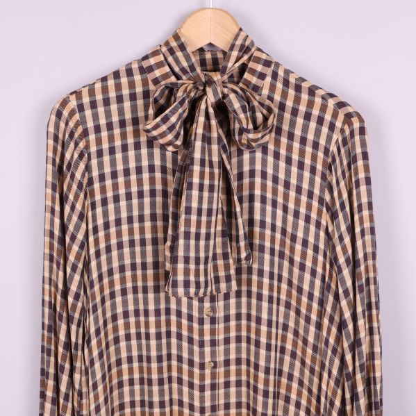 Närbild på knytband vid halsen och rutigt mönster