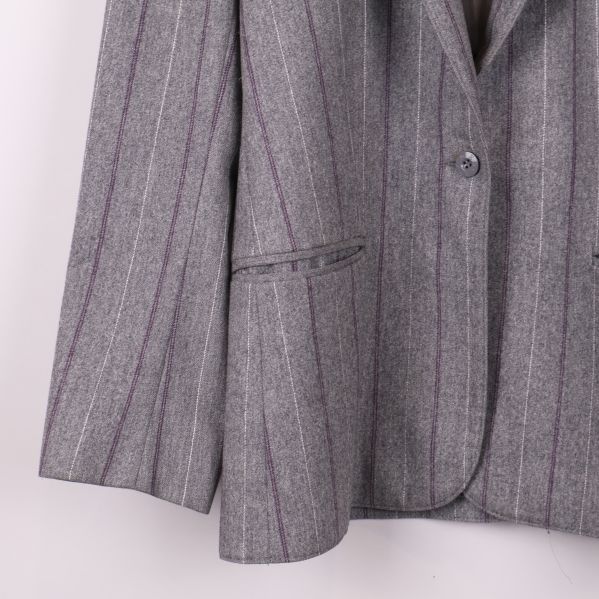 Detaljbild på vänster ficka och nederdel av grå kavaj