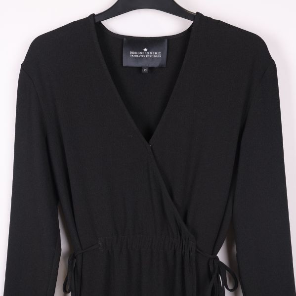 Närbild omlottkrage och midja med knytband på svart klänning