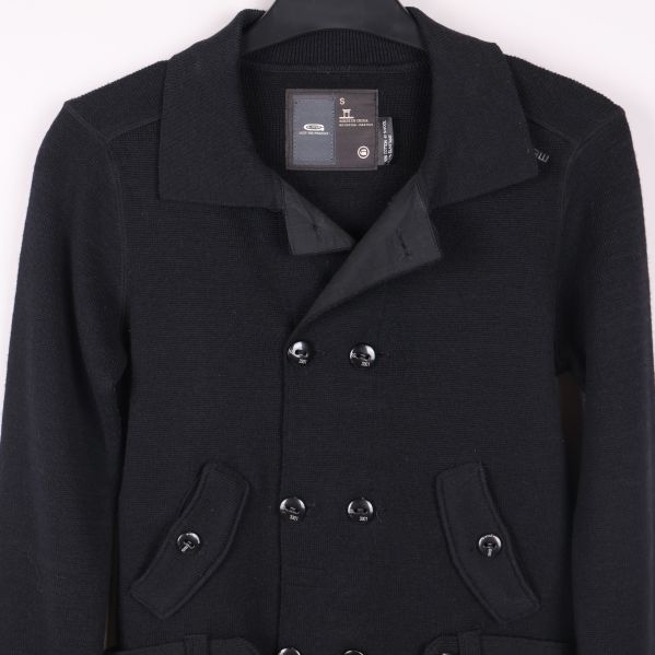 Övre delen av svart kofta med knappar och fickor