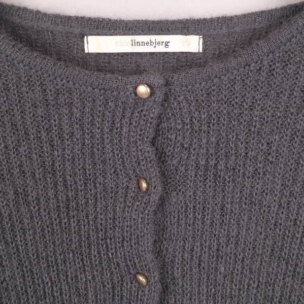 Närbild på koftans knappar och varumärkesetikett