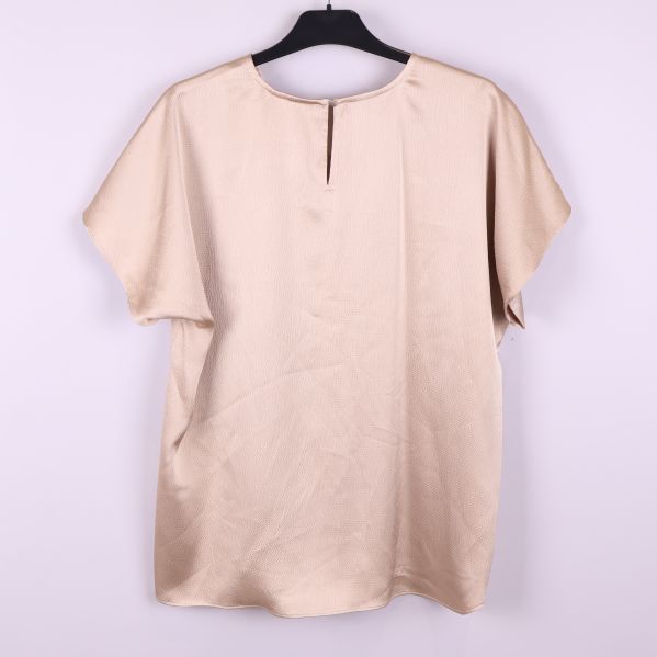 Baksida på beige strukturerad blus med kort ärm